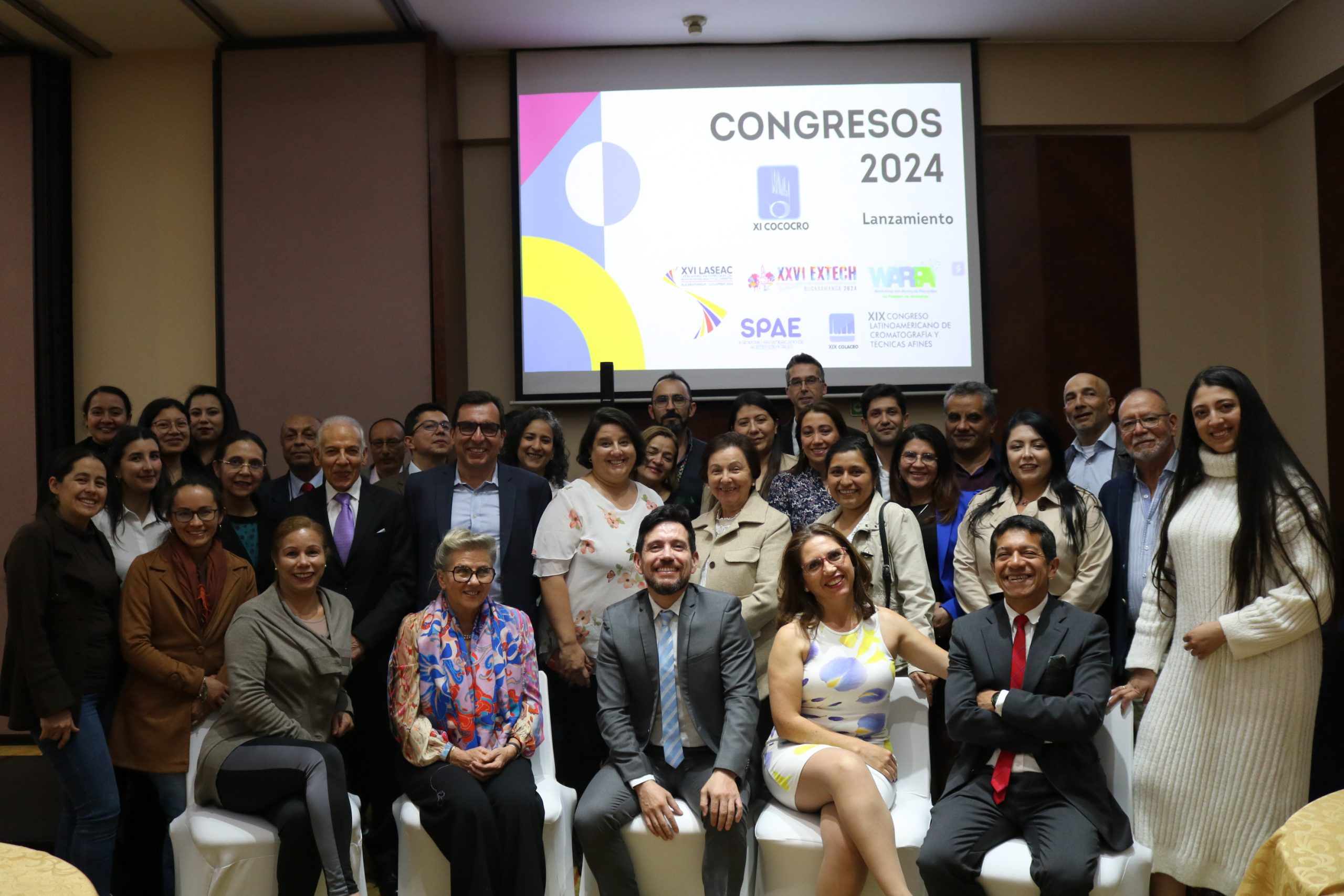 Grupo de aproximadamente 35 asistentes posando en el lanzamiento de los Congresos 2024, con pantalla de presentación al fondo.
